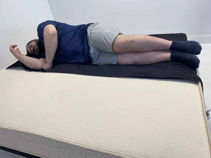 A man lying on his side on the Birch Natural mattress.