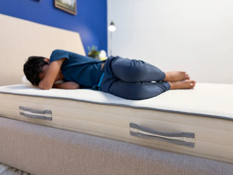 A mattress tester side sleeping on the edge of the Nolah Nurture mattress.