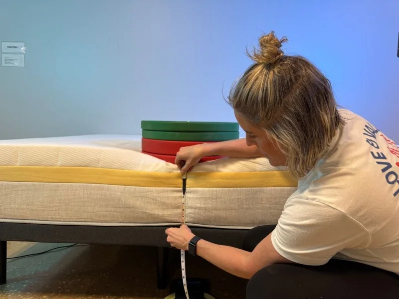 Our tester measuring weight plates on a Helix Dawn Mattress