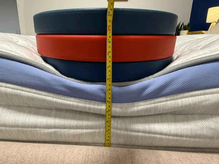 Three weight plates are stacked on the edge of the Helix Moonlight to measure the sinkage with a tape measure