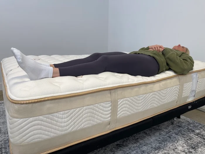 A woman lying on her back on the Saatva Rx.