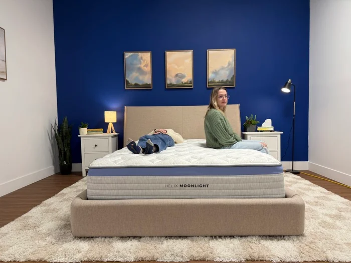 A person lies on one side of the Helix Moonlight while another sits on the edge on the other side