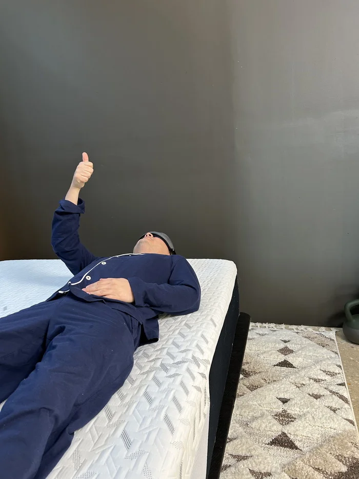 A tester lies blindfolded on the Nectar Classic during our motion isolation test, giving a thumbs up to show he felt his partner's movement