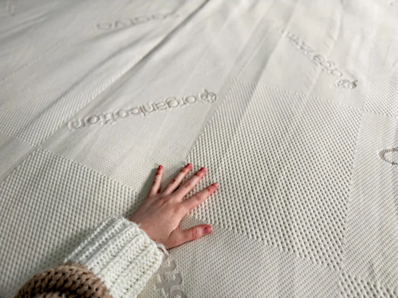 Someone feeling the texture of the Saatva Natural Latex Mattress Topper.