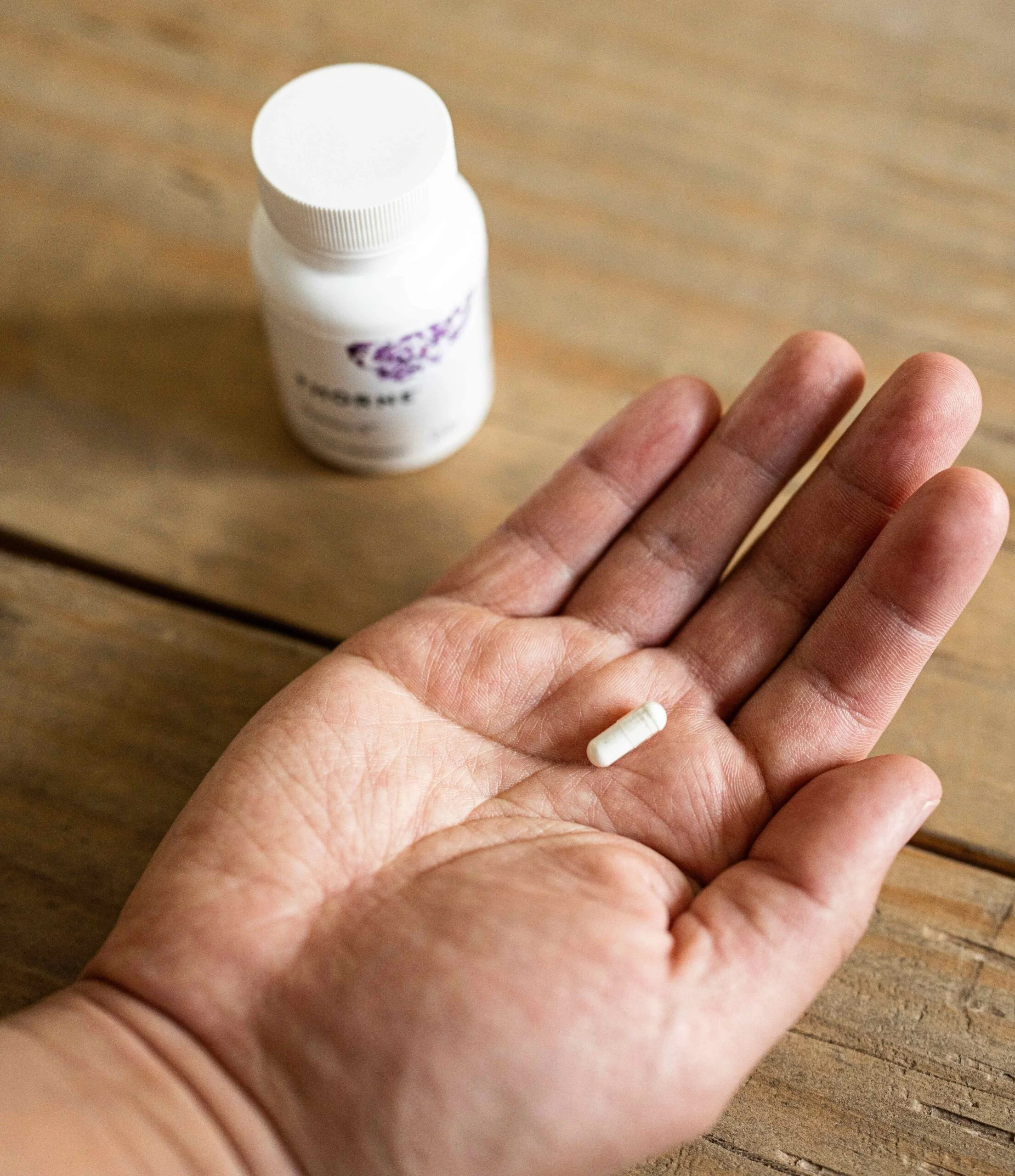 Our tester holds a tiny Thorne Melatonin 5mg capsule.