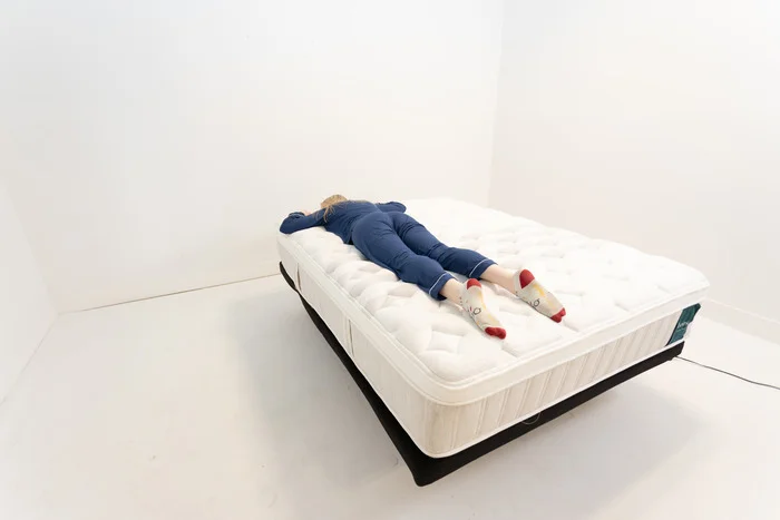 A woman lying on the Leesa Sapira Chill Hybrid mattress on her stomach.