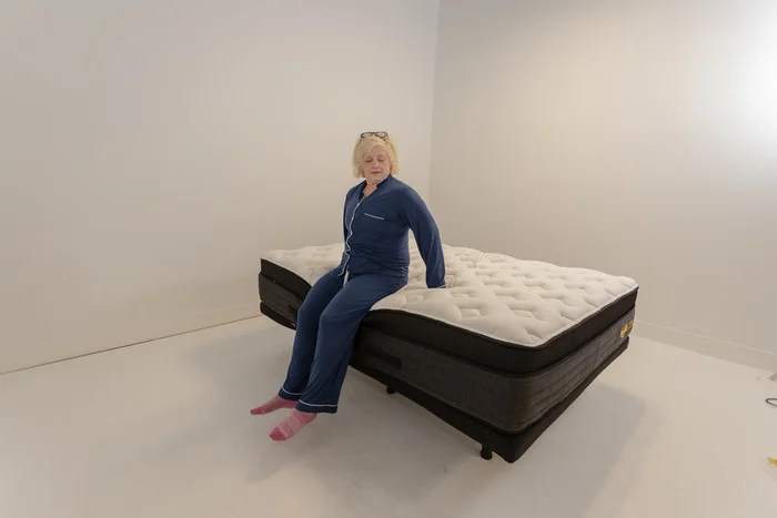 A woman sitting on the edge of the Nolah Evolution mattress to test its edge support.