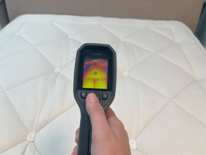 A closeup of a thermal gun reading the temperature of the Avocado Luxury Organic mattress after someone has rested on it for 5 minutes.