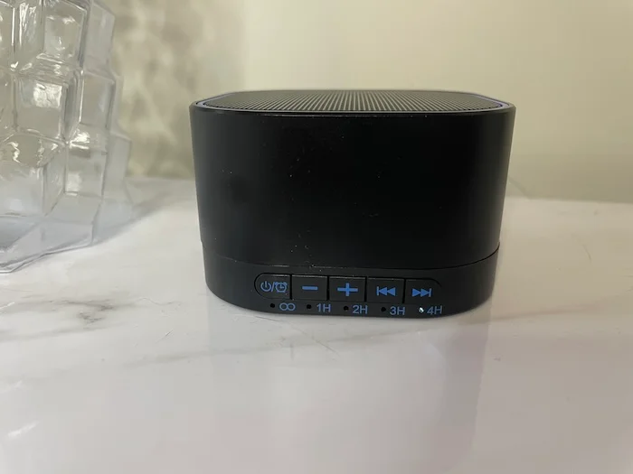 A closeup of a Magicteam Sound Machine sitting on a marble countertop.