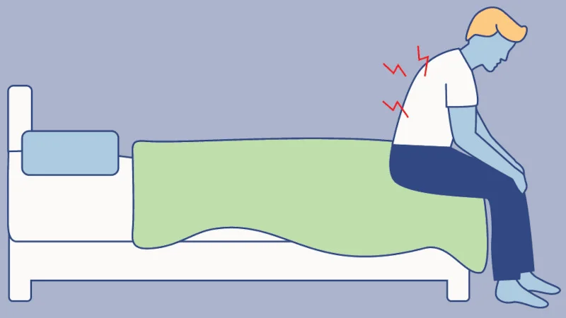 An illustration of a person sitting on the edge of a bed with back pain