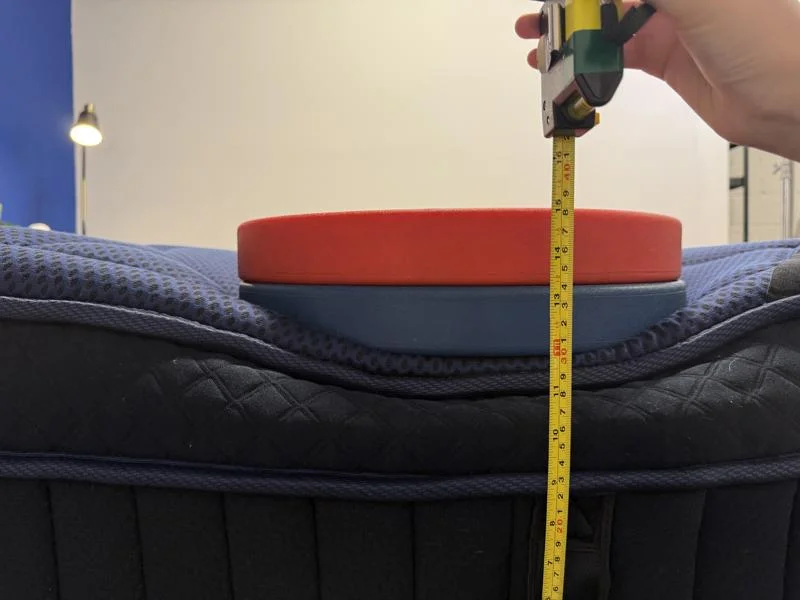 Measuring weight plates on the edge of the DreamCloud Ultra Hybrid Mattress