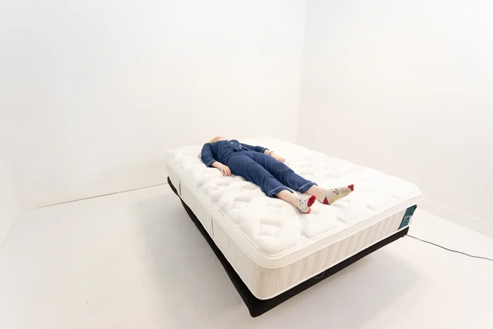 A woman lying on her back on the Leesa Sapira Chill Hybrid mattress.