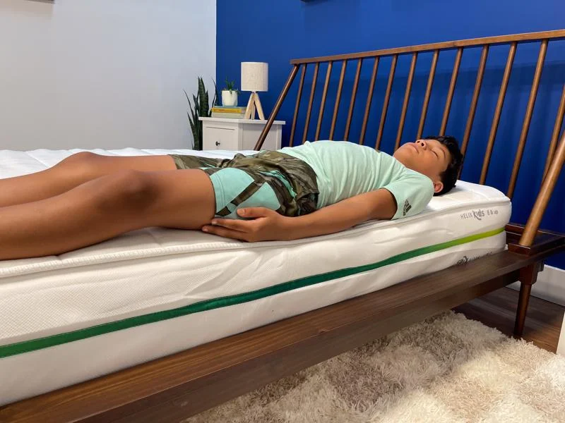Our young tester performs a back-sleeping full body edge support test of the Helix Kids 8-Inch Mattress