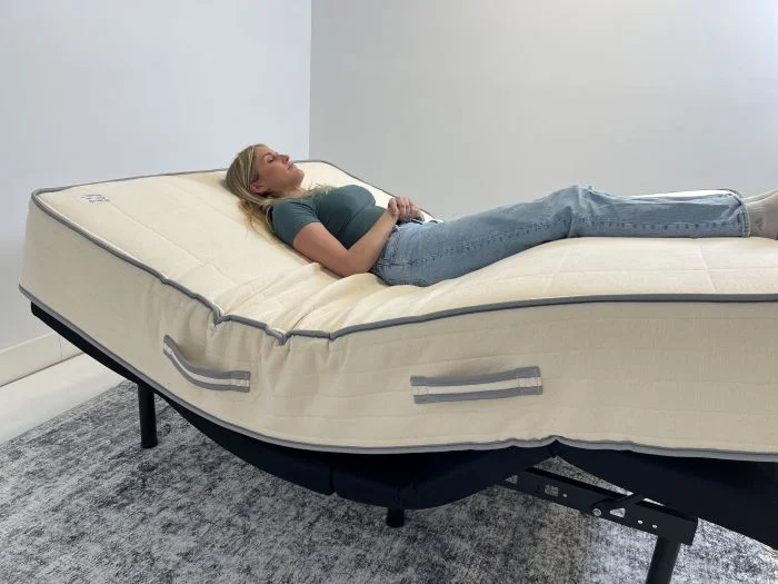 A woman lying on a Nolah Natural mattress while it's on top of an adjustable base.