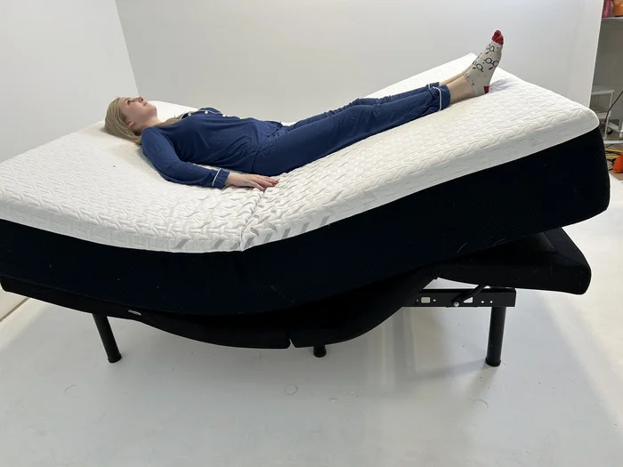 A woman lying on her back on the Nectar mattress while it's on an adjustable base.