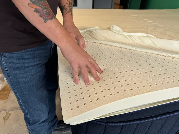 Our tester touches the latex insert in a Silk & Snow Organic Mattress Topper