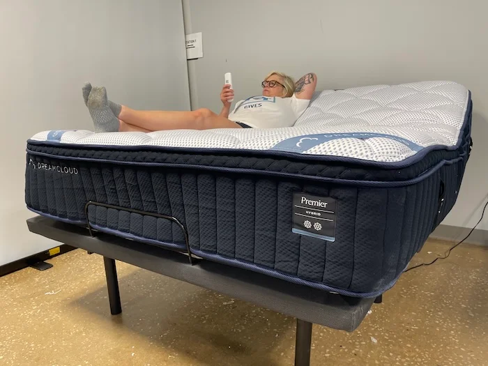 A woman lying on the DreamCloud Premier Hybrid mattress on top of an adjustable base.