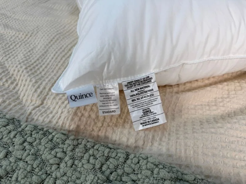 A close up photo of the Quince Down Alternative Pillow tags showing the material and care instructions