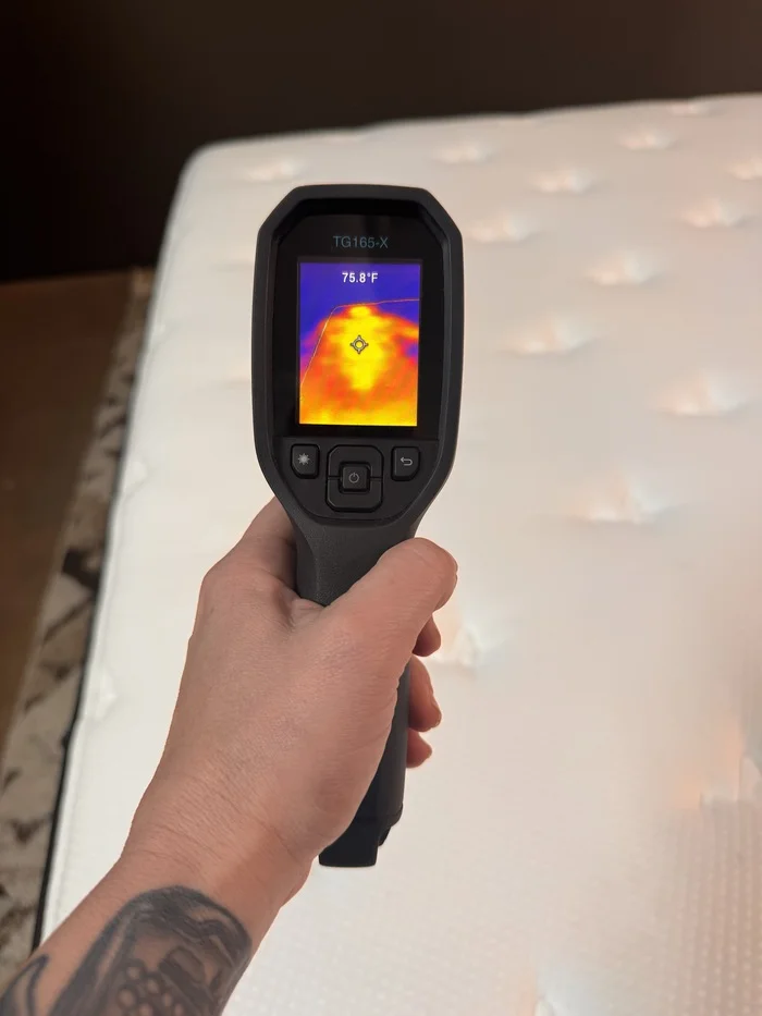 A closeup of someone aiming a thermal gun at the Plank Firm to read its surface temperature after someone has rested on it for 5 minutes. The temperature reads 75.8 degrees.