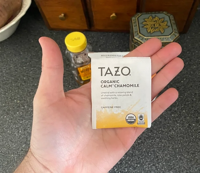 Our tester holds a Tazo Calm Chamomile tea bag in their hand.