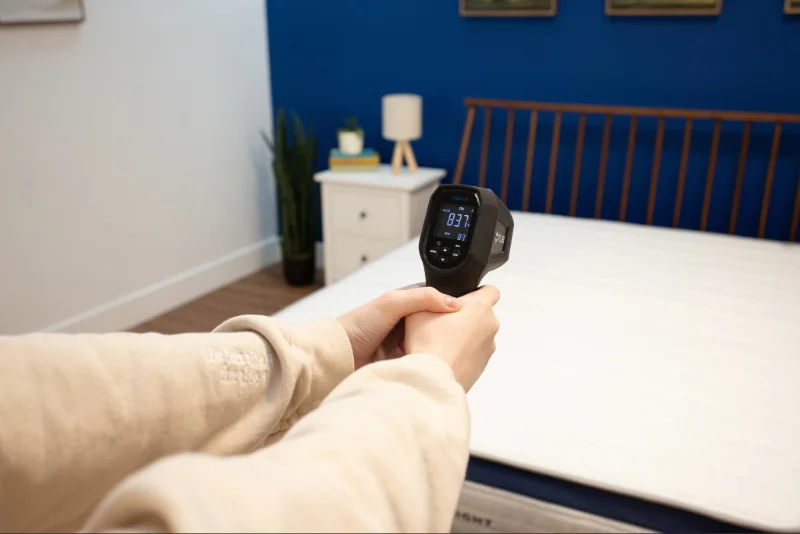 A mattress tester using a thermal gun to measure the surface temperature of the Helix Midnight.