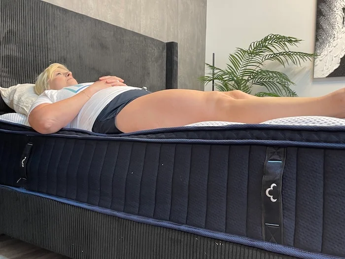 A woman lying on her back on the DreamCloud Premier Hybrid mattress.