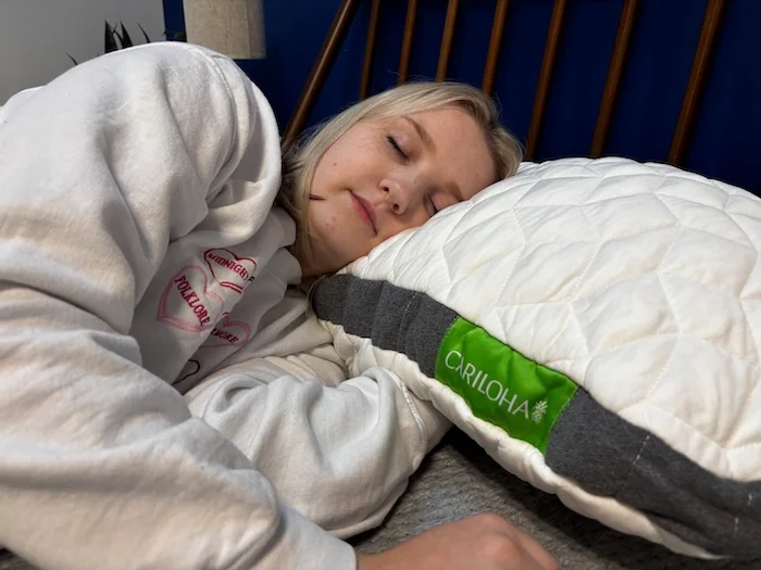 Riley rests on her side with a Cariloha Resort Pillow