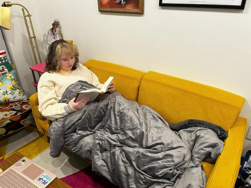 Our sleep expert relaxing on the couch with a Luxome Weighted Blanket
