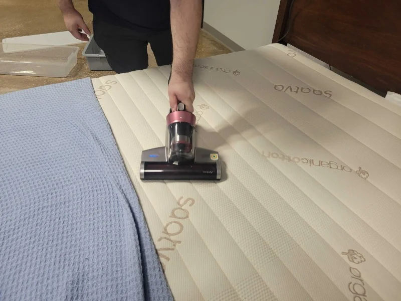 A person vacuuming a mattress with the Jimmy BX5 Pro 120V-Corded vacuum.