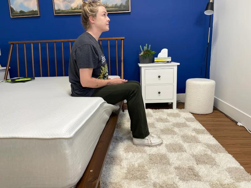 Our tester performs a seated test to assess the edge support of a Boring Hybrid Mattress.
