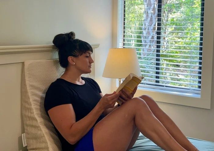 Our expert reads a book while lounging on an Avocado Organic Wedge Pillow.