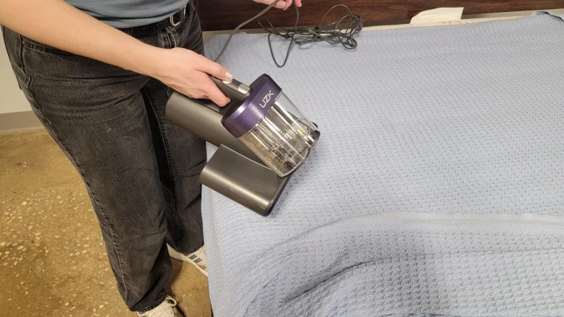 A person strings out the cord to use a UZK vacuum cleaner.