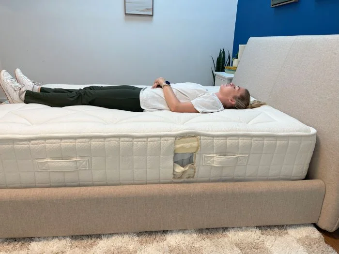 A woman lying on her back on the Avocado Luxury Organic mattress.