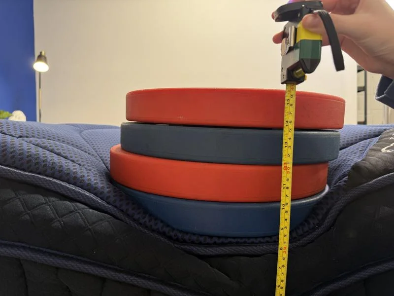 Measuring weight plates on the edge of the DreamCloud Ultra Hybrid Mattress