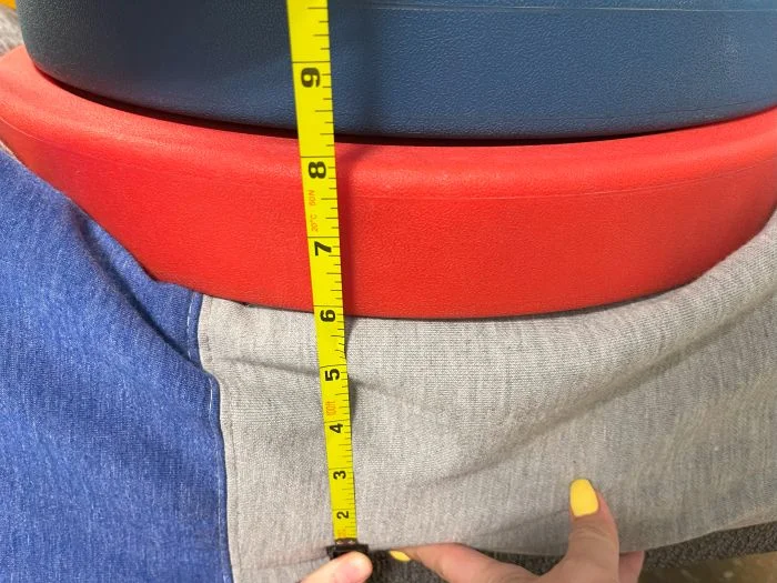 A stack of weights on top of a Casper The One mattress, with a tape measure measuring the sinkage.