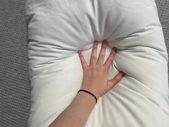 A closeup of a hand pressing into the Parachute Down Alternative Body Pillow.