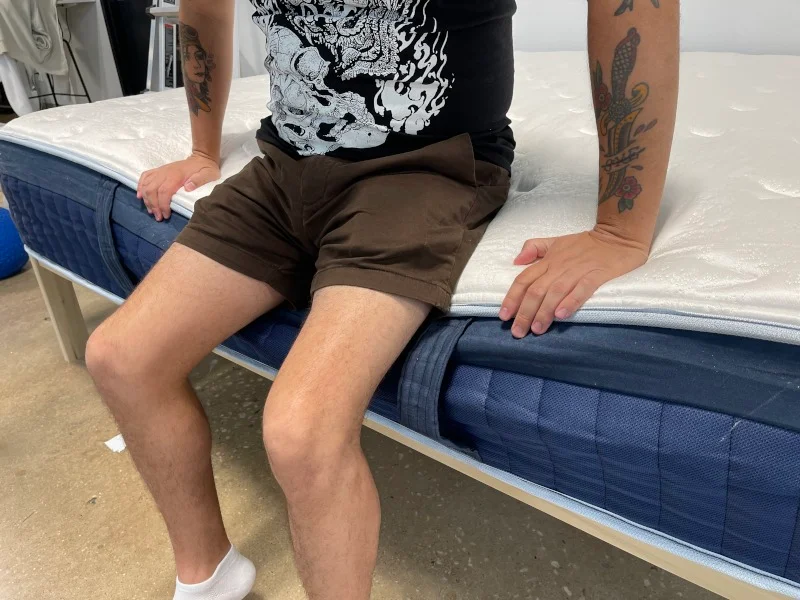 Our tester performing an edge support test on a Glacier Summit Hybrid Mattress