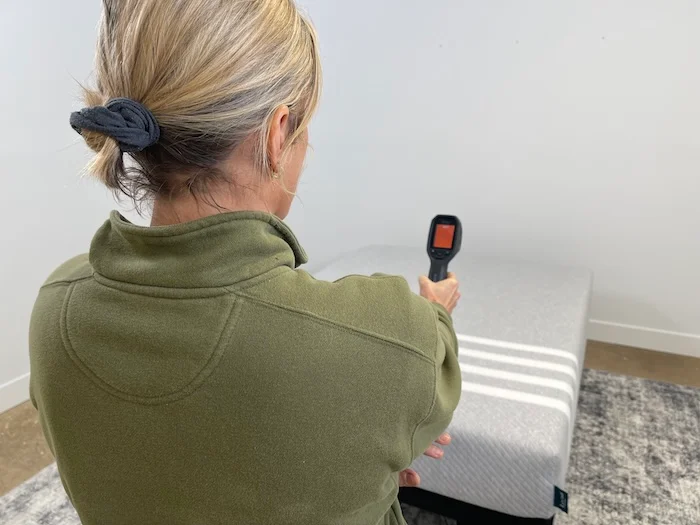 A woman aiming a thermal gun at the Leesa Original mattress to read its temperature.