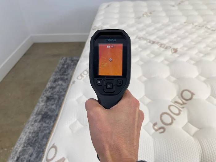 A closeup of someone using a thermal gun to take the neutral temperature of the Saatva Rx. The screen reads 68.7 degrees.