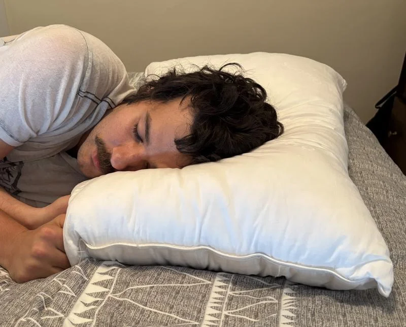 Our tester side-sleeping on a Saatva Down Alternative Pillow
