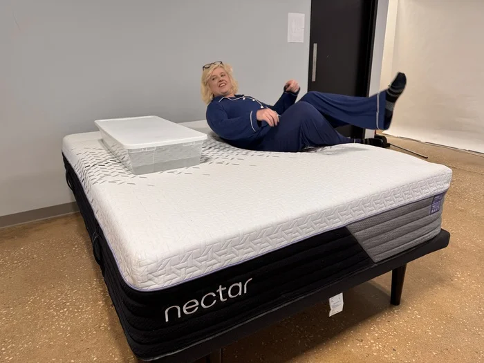 A woman rolling back and forth next to a bin full of water on the Nectar Luxe Hybrid mattress to measure its motion isolation.
