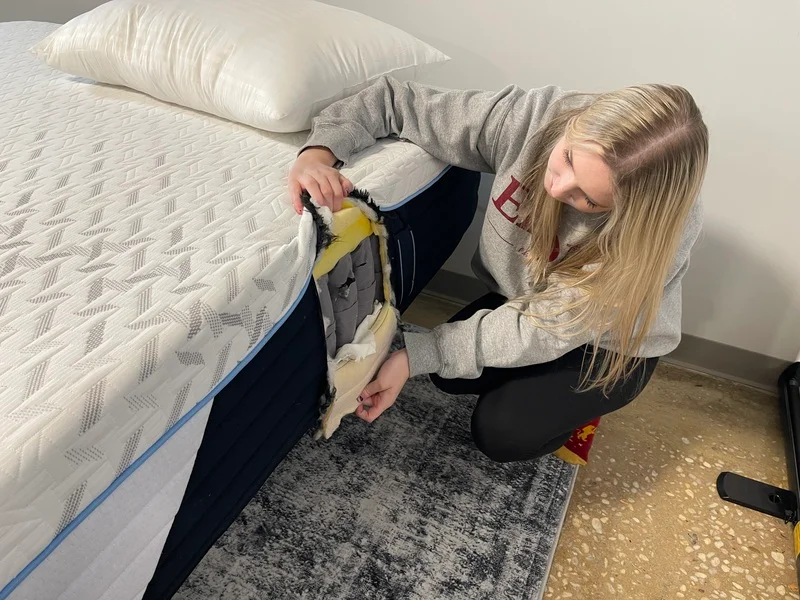 A mattress tester cuts into the layers of the Nectar Classic Hybrid