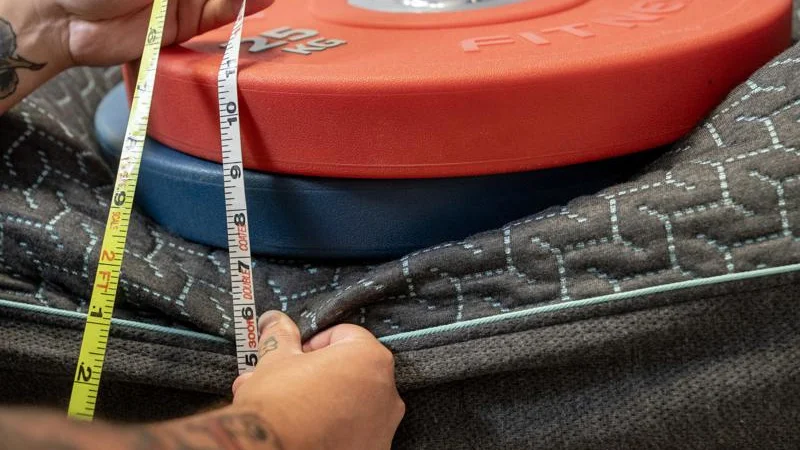 Our tester measures the sinkage from weight plates along the edge of the Tuft & Needle Mint Hybrid Mattress