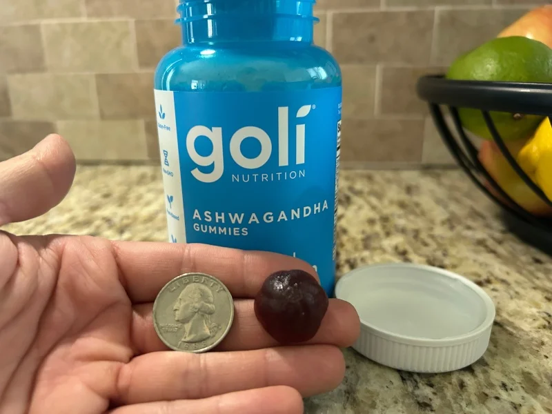 Our tester holds a Goli Ashwaganda Gummy next to a quarter for size comparison.
