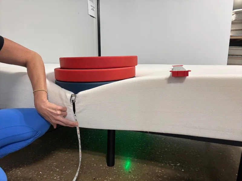 Our tester measuring weight plates on the edge of a PolySleep Sierra Mattress