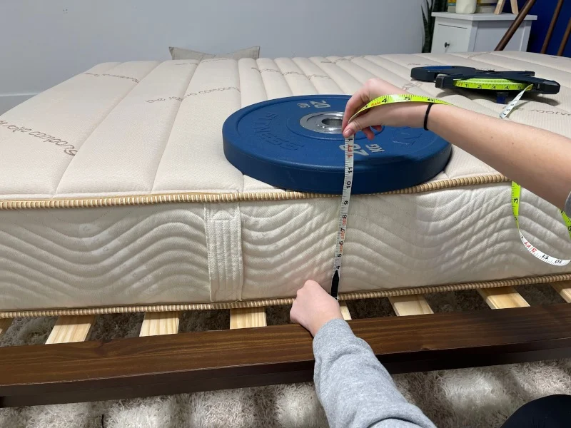 Our tester measures the compression of weight plates to assess edge support on a Saatva Youth Mattress