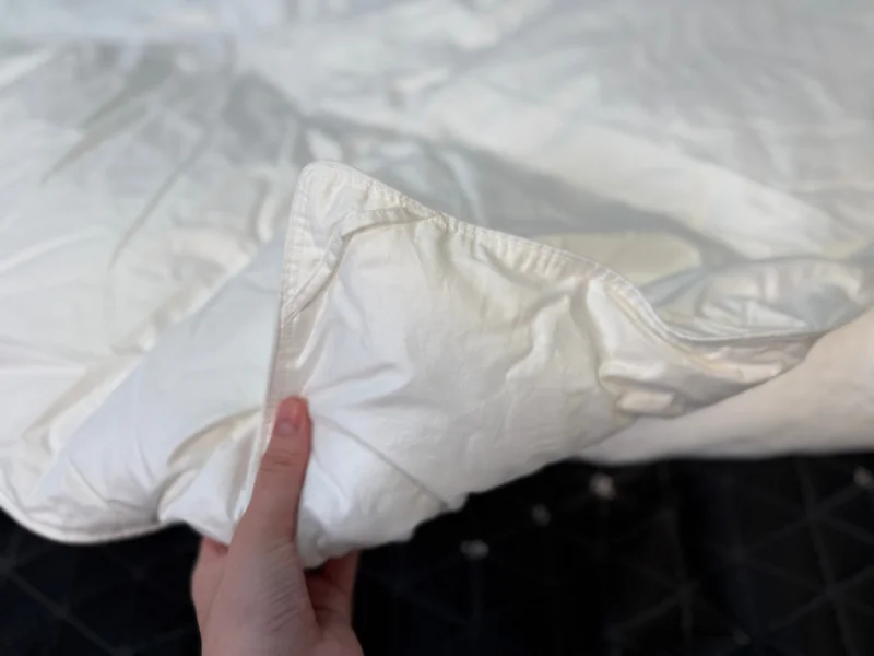 Our tester holding up a corner of the Quince Down Alternative Duvet Insert to show the materials.