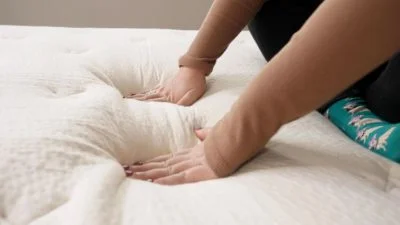 One of our mattress testers pressing into the cover of the Birch mattress to test its responsiveness.