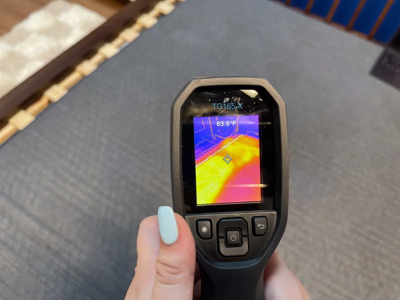 A closeup of a thermal gun reading of the temperature of the BB Kids mattress after someone has rested on it for 5 minutes. The screen reads 83.6 degrees.