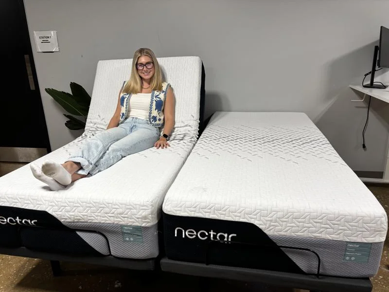 Our tester smiles while lounging on a Nectar Premier Adjustable Base with Nectar Split King mattresses